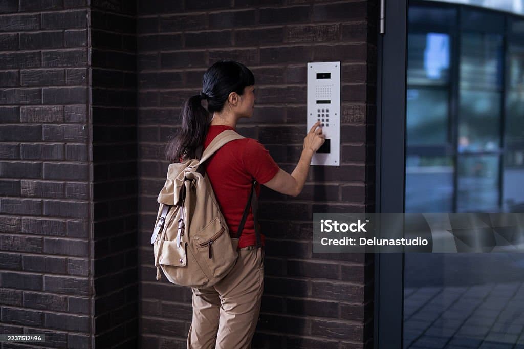 Resident entering a code at a wall-mounted keypad and intercom panel